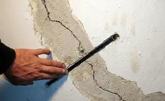 A wall with a large crack is being inspected by a professional in Duluth, MN